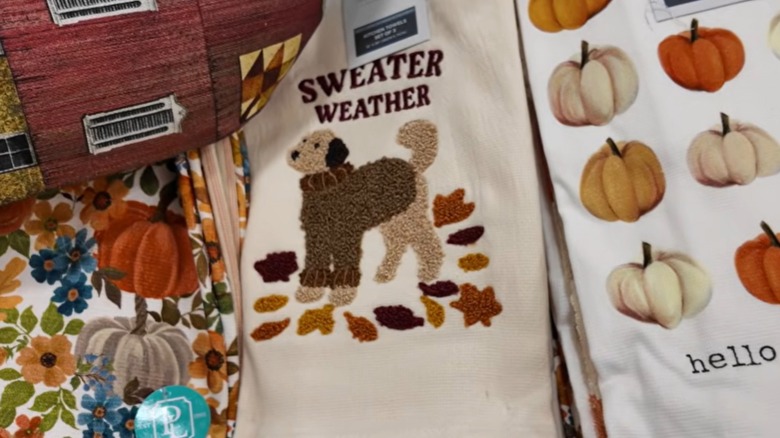 Paño de cocina con hojas, perro con suéter y 