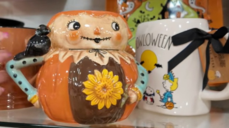 Taza sonriente con forma de espantapájaros y girasol en el frente.