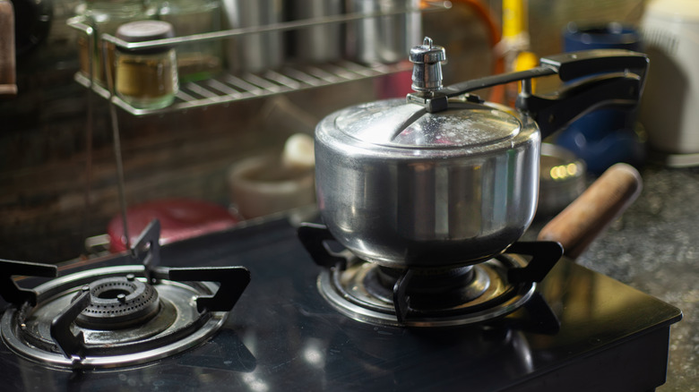Una olla a presión plateada sobre una pequeña estufa de gas.