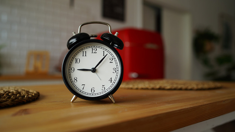 Un reloj despertador negro vintage sobre una encimera de cocina de madera