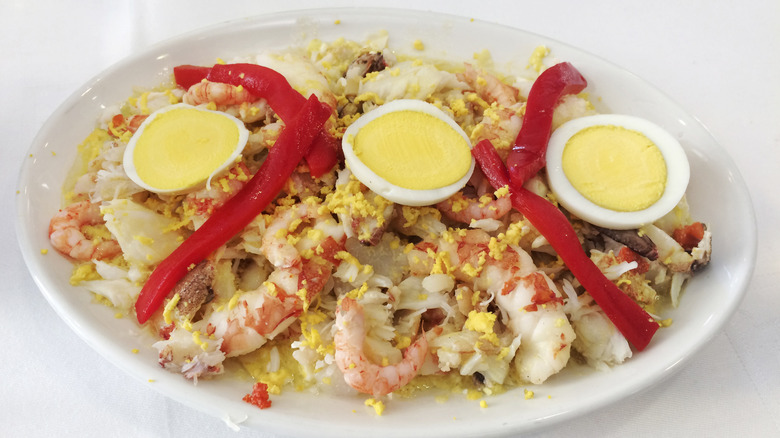 Plato de marisco mixto con huevos cocidos y pimientos rojos asados