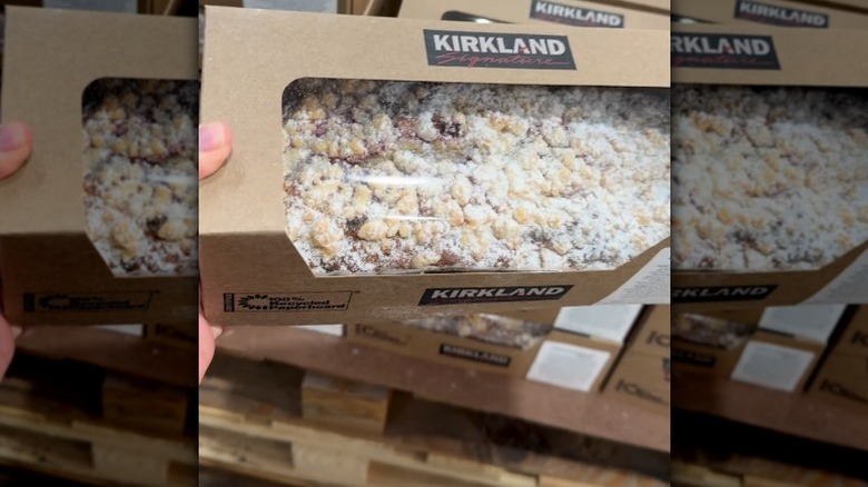 Mano sosteniendo cartón de pan de limón y frambuesa.