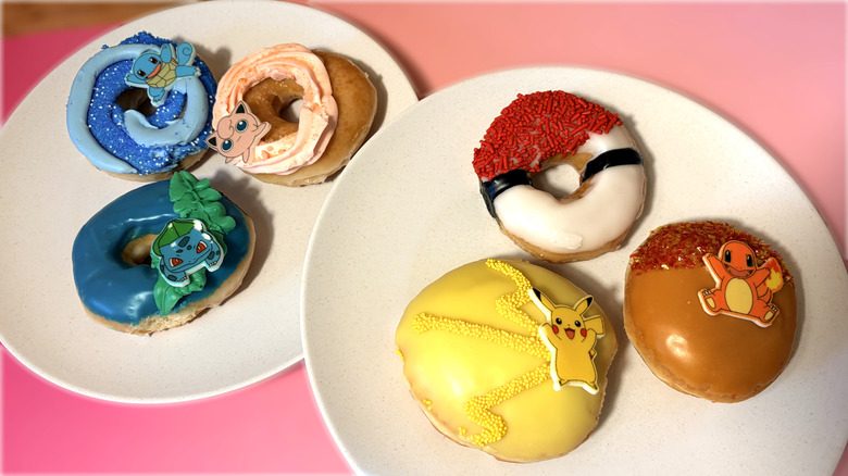 Variedad de donuts Krispy Kreme con temática de Pokémon en platos.