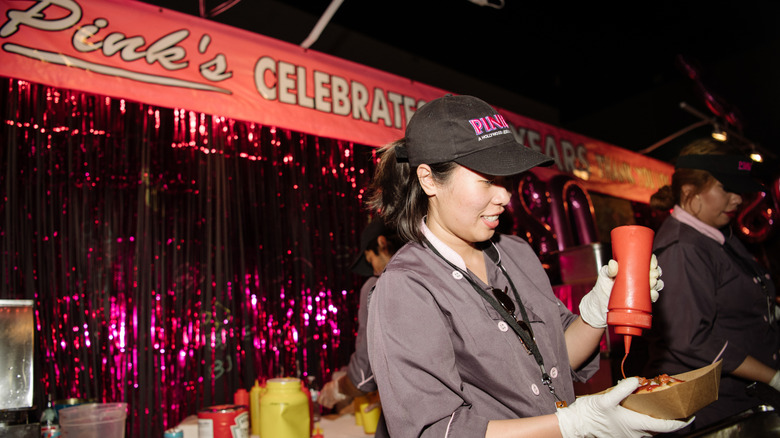 Un trabajador de Pink's Hot Dogs haciendo un hot dog.