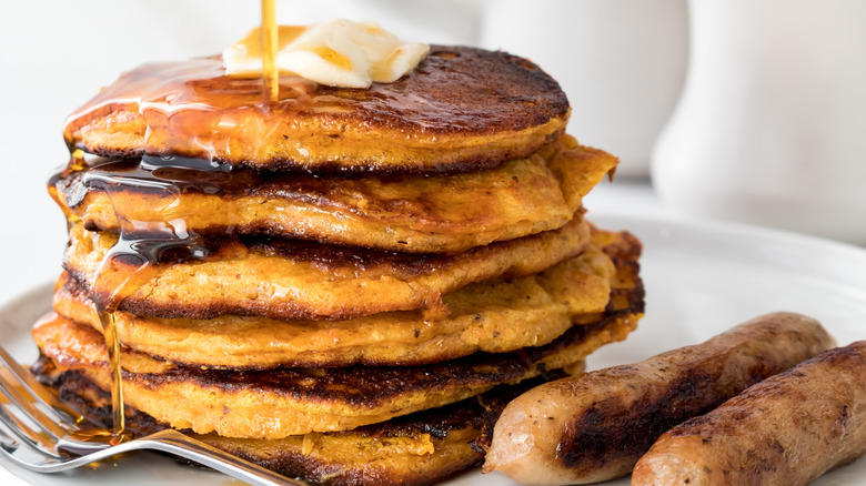 Pila de tortitas de batata con sirope de arce y salchichas