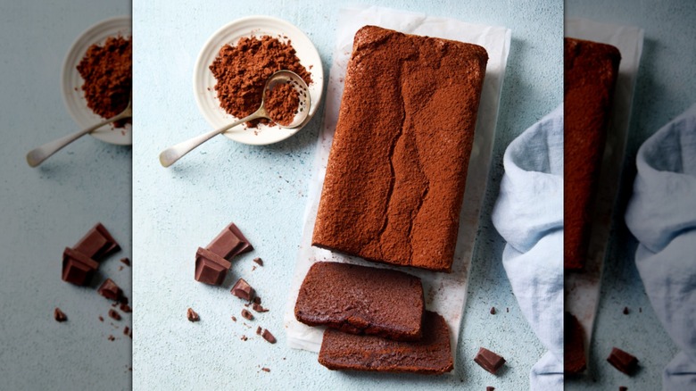 Un pastel de chocolate espolvoreado con cacao en polvo sobre una tabla para cortar