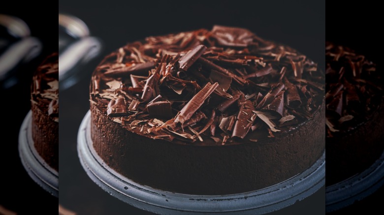 Un pastel de chocolate con virutas de chocolate encima sobre un pedestal
