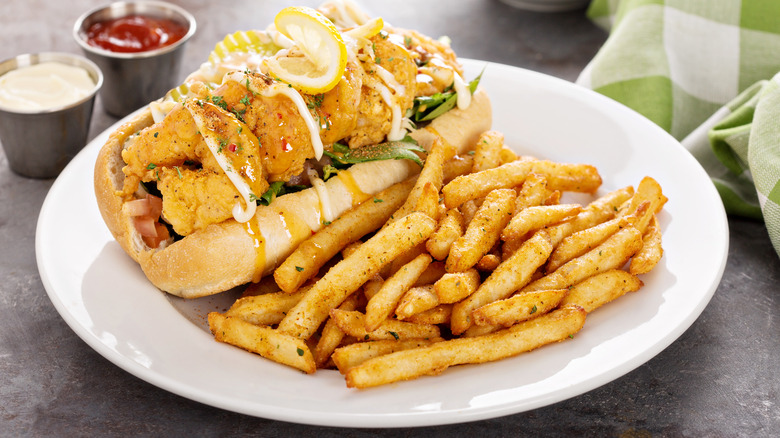 Po' boy de camarones con papas fritas en plato blanco