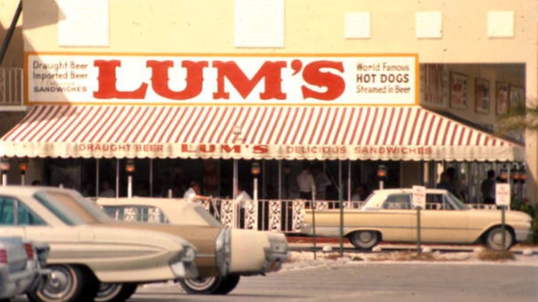 Exterior de LUM con un toldo a rayas y un gran letrero con letras rojas