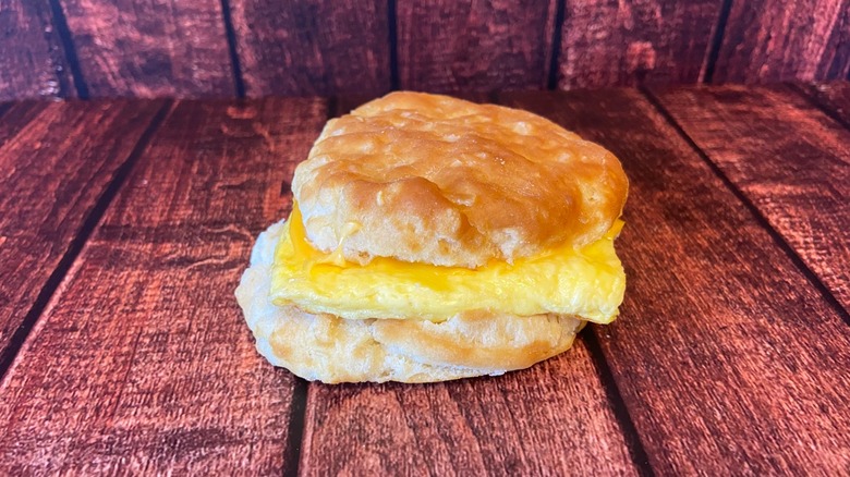 Una galleta de huevo, queso y tocino sobre una mesa de madera