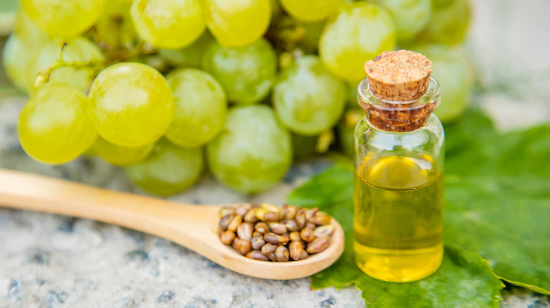 Botella de aceite de semilla de uva con uvas al fondo