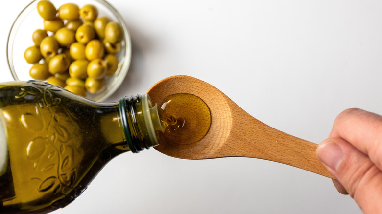 Verter aceite de oliva de la botella a la cuchara