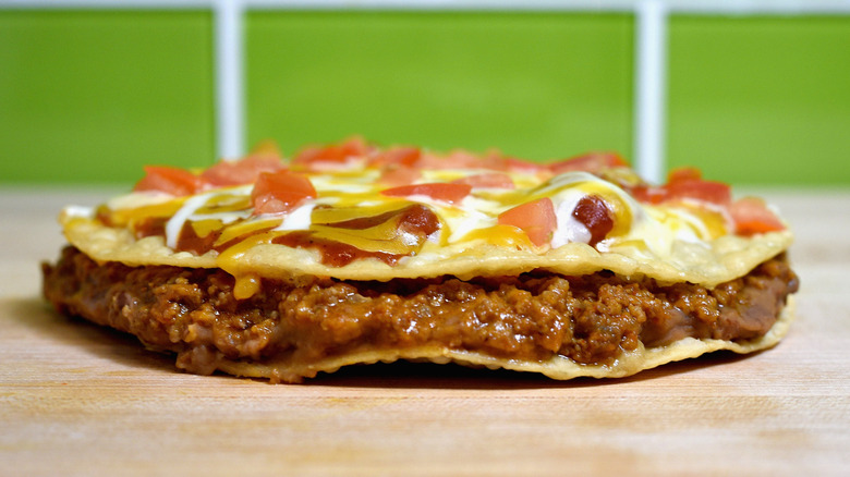 Una pizza mexicana Taco Bell sobre una mesa de madera con fondo verde