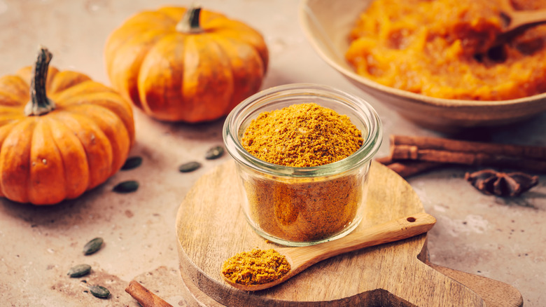 Mezcla de condimentos de calabaza y especias en un molde de vidrio transparente, con puré de calabaza y calabazas pequeñas