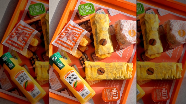 Bandeja Whataburger de burritos de desayuno envueltos y una galleta con jugo de naranja Simply y palitos de hash brown