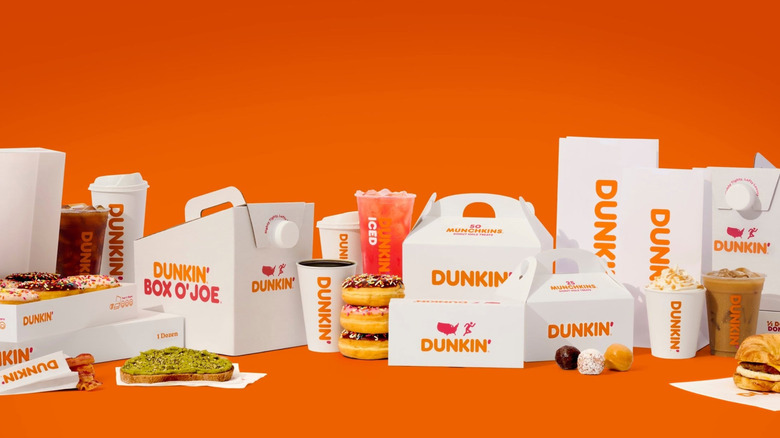 Variedad de alimentos y bebidas Dunkin' para el desayuno sobre un fondo naranja