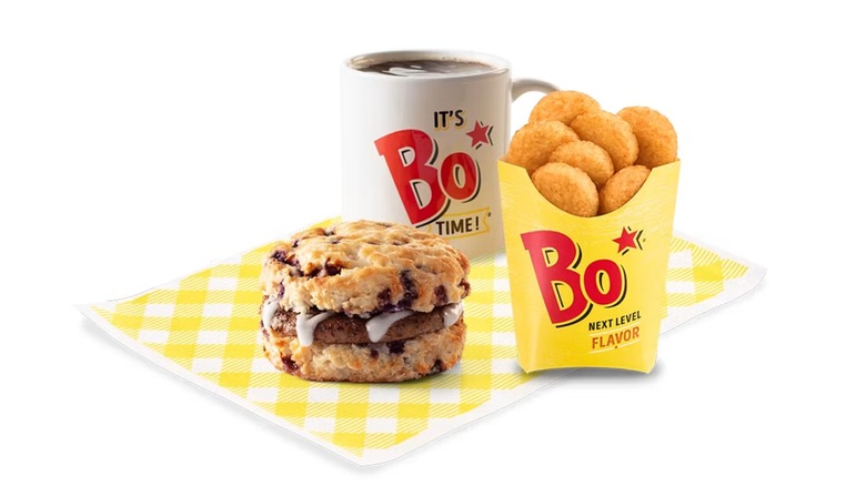 Bojangles Sausage Bo-Berry con galletas Bo-Tato Rounds y café en una taza con el lema sobre un fondo blanco
