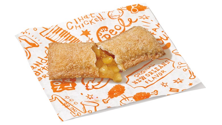 Una tarta de manzana con canela Popeyes abierta sobre un fondo blanco