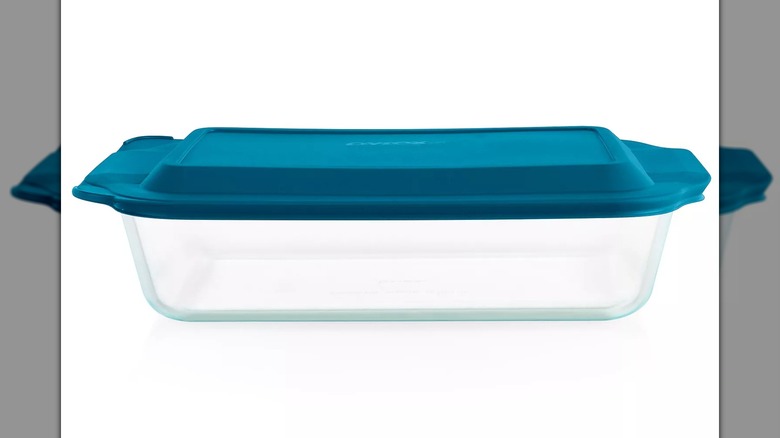 Fuente para hornear de vidrio Pyrex profunda con tapa sobre un fondo blanco.
