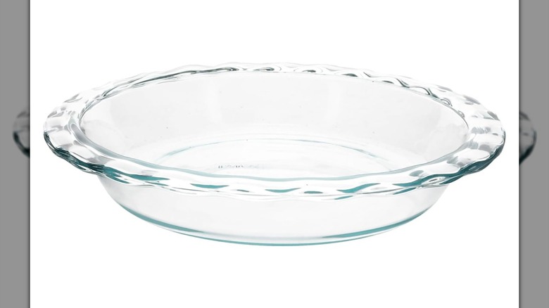 Plato de pastel de borde estriado de vidrio Pyrex sobre un fondo blanco.