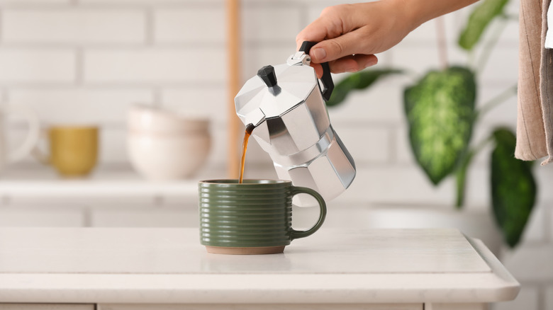 Persona sirviendo espresso de una moka en una taza