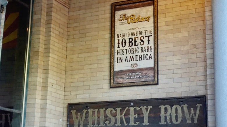 Dos carteles fuera del Palacio, uno nombrándolo uno de los mejores bares históricos y el otro etiquetado 