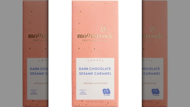 Barra de chocolate oscuro y caramelo de sésamo Moonstruck en un envoltorio rosa pálido sobre fondo blanco