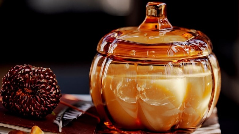 IKEA Höstagille vela con aroma a calabaza especiada en vidrio de color marrón sobre una pila de revistas