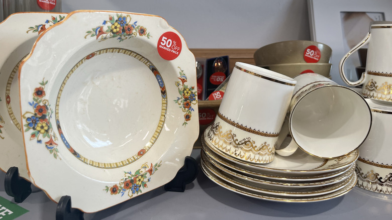 Vajilla con pegatinas de descuento en el estante de una tienda de segunda mano