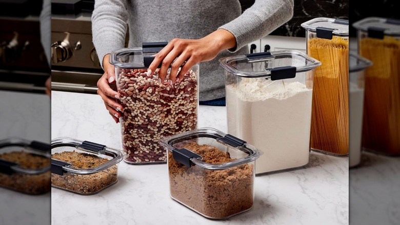 Una mano cerrando un contenedor hermético de despensa Rubbermaid Brilliance sobre una encimera