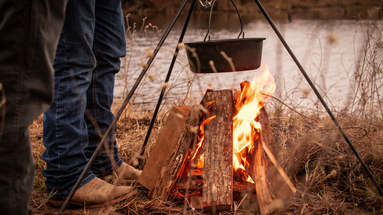 Vaqueros cocinando comida en un horno holandés.