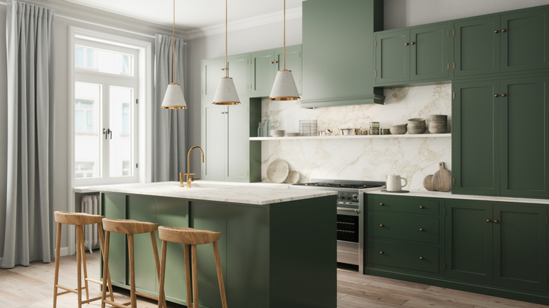 Una cocina con gabinetes de color verde bosque, encimeras blancas y taburetes de madera clara.