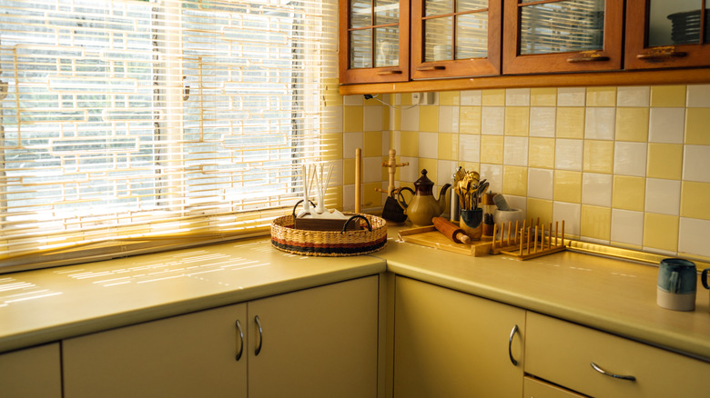 Una cocina vintage con gabinetes, encimeras y azulejos de color amarillo mostaza.