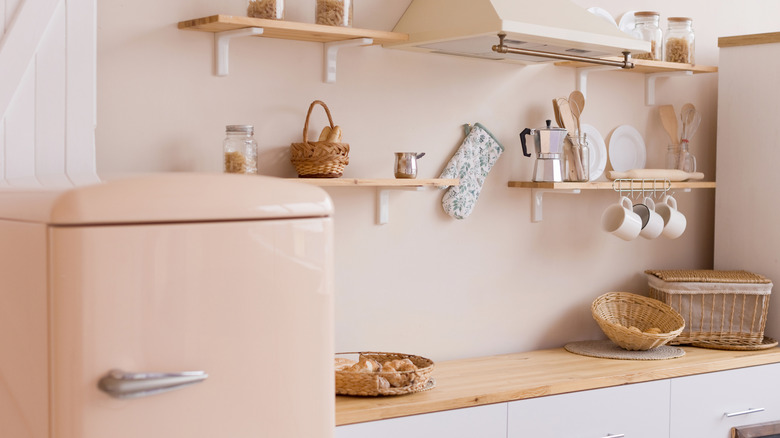 Una cocina retro con paredes de color beige rosado y refrigerador.