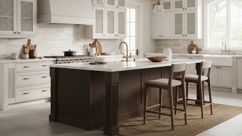 Isla de cocina con encimera de mármol y base pintada de marrón en una cocina blanca