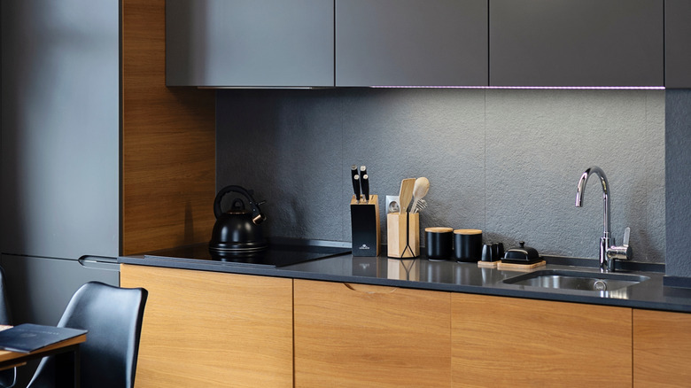 Una cocina moderna con gabinetes de madera grises y marrones.