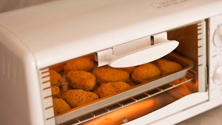 Nuggets de pollo en una bandeja de chapa metálica en un horno tostador blanco