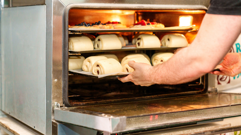 Cargando un horno tostador con muchos pasteles crudos