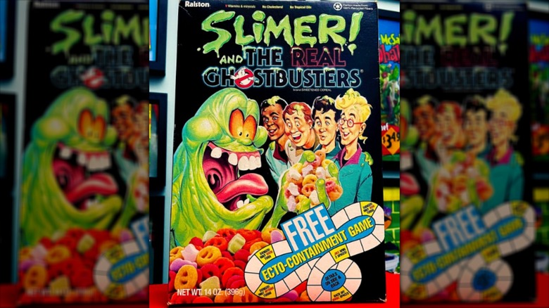 Caja de cereales de los Cazafantasmas de los 90 con Slimer sosteniendo cereal y cuatro personas.
