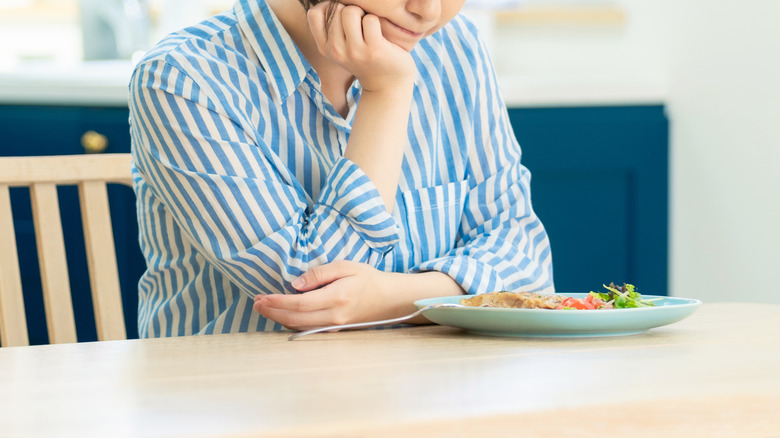 Mujer decepcionada con un plato de verduras