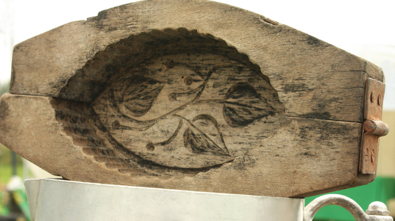 Un molde de mantequilla de madera tiene un diseño de hoja tallado en el interior.