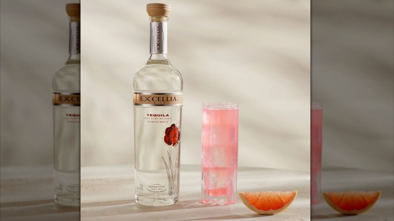 Botella de Excellia Blanco junto a un cóctel rosa en un vaso
