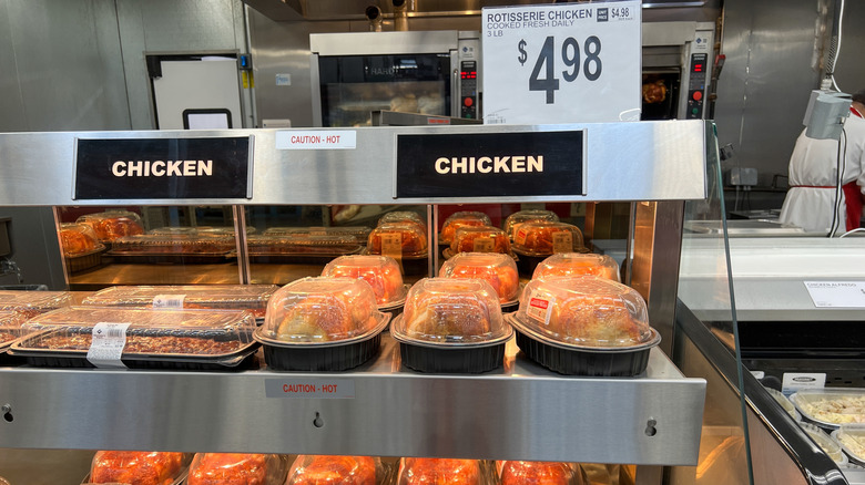 Cajas de pollo asado de Sam's Club se encuentran bajo lámparas de calor.