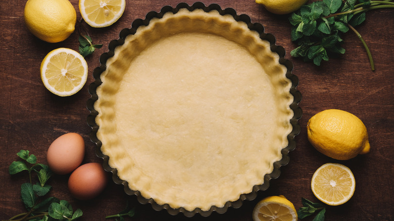 Molde de hojaldre forrado con masa y rodeado de limones y huevos.