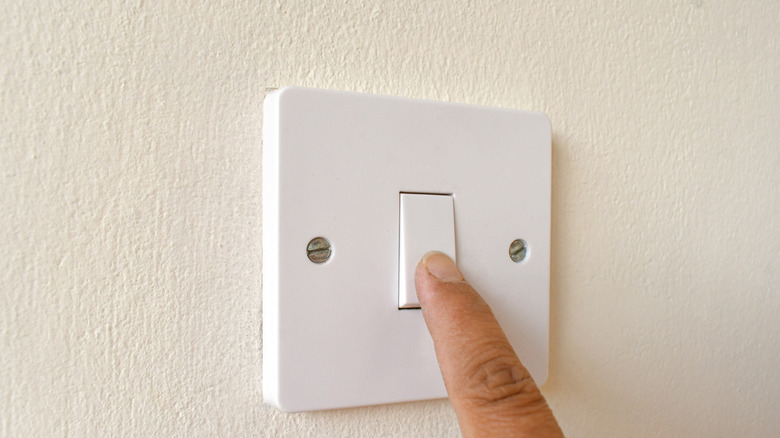 Dedo presionando el interruptor de la luz en la pared