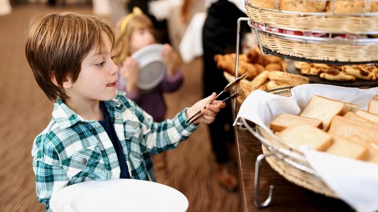 Niño sirviéndose solo en el buffet