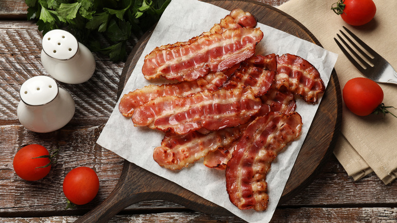 Tocino frito fino sobre una tabla para cortar nueces