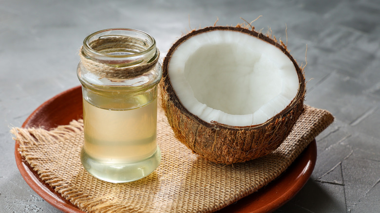 Medio coco y tarro de aceite de coco.