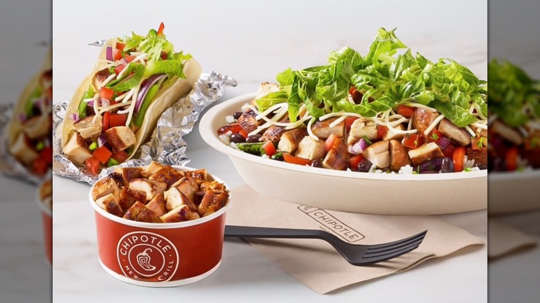 Tazón doble alto en proteínas de Chipotle junto a otros elementos del menú ricos en proteínas en un mostrador blanco