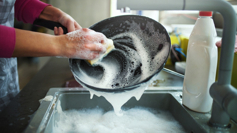 Persona fregando una sartén con agua y jabón